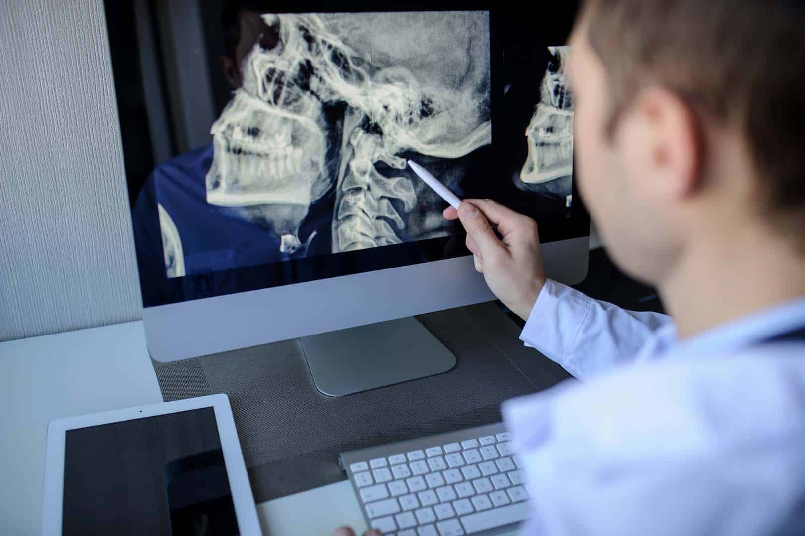 back view of a male radiologist examining neck x rays (cervical